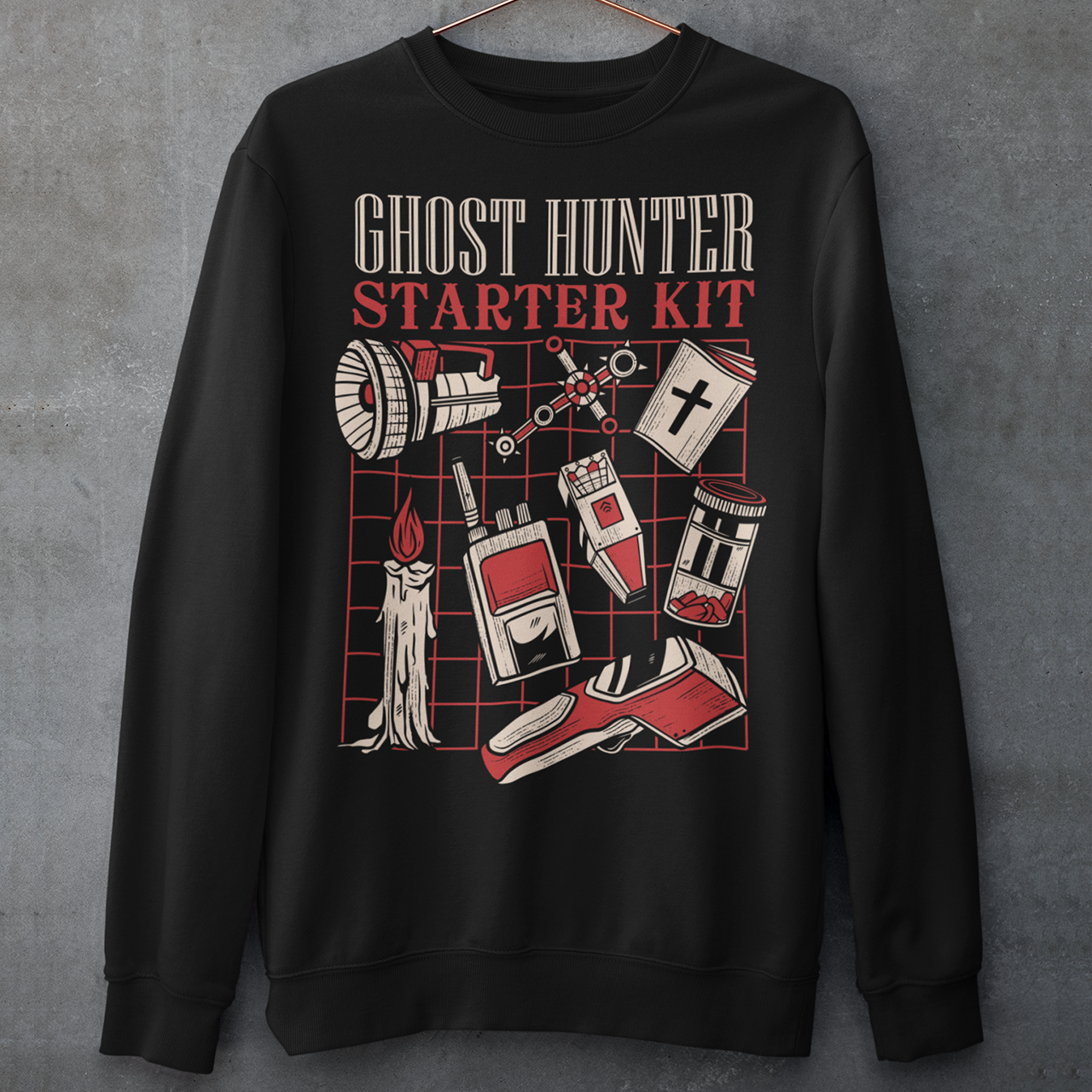 Step into the shadows with this Ghost Hunter Starter Kit sweatshirt, a perfect blend of spooky humor and paranormal adventure. Designed for fans of ghost hunting, horror culture, and all things supernatural, this bold graphic tee features a vintage-style layout packed with classic ghost hunting essentials like an EMF reader, flashlight, candle, spirit box, holy book, and more. The striking red and off-white artwork pops against the black fabric, giving it a retro paranormal investigator vibe.