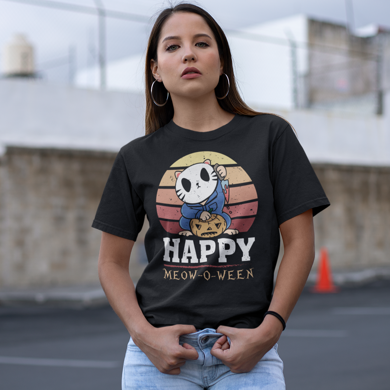 Black halloween t-shirt of a cat in a horror costume with retro sun background with text underneath  "HAPPY MEOW-O-WEEN".