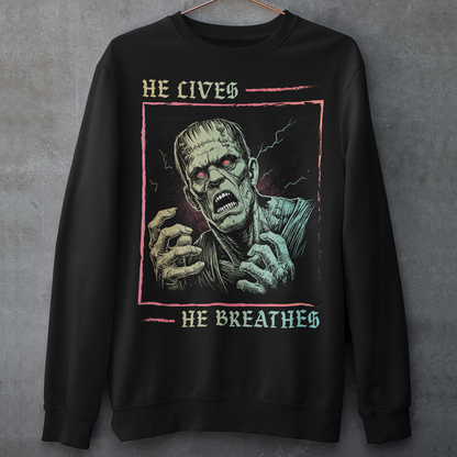 Black sweatshirt of Frankenstein with text above HE LIVES and text below HE BREATHES.