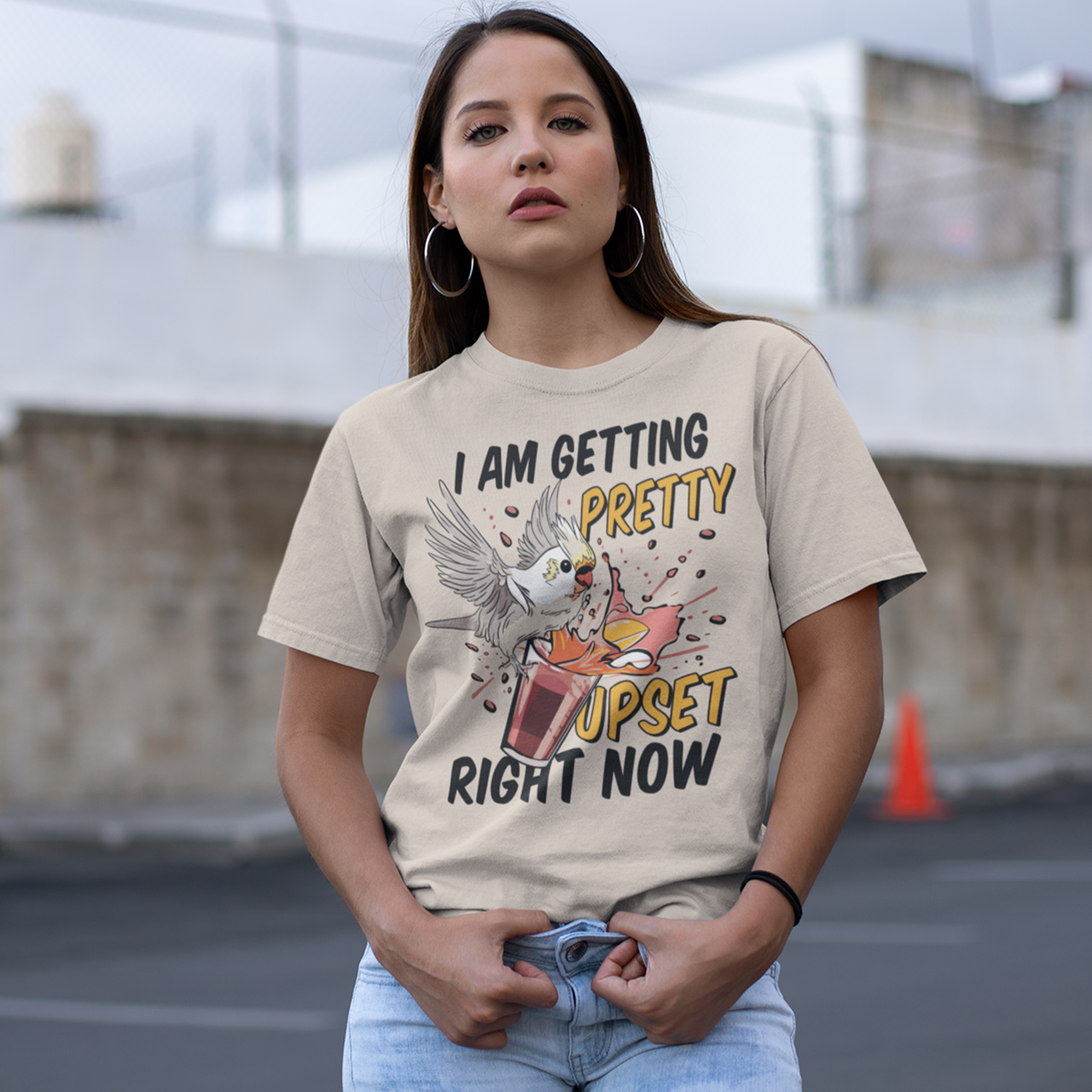 Cream t-shirt of cockatoo knocking over a cocktail with text underneath "I AM GETTING PRETTY UPSET RIGHT NOW".