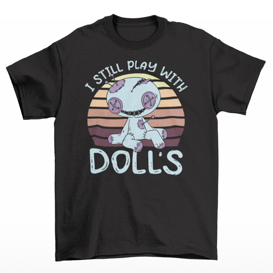 Black t-shirt of a voodoo doll with a retro background with text  "I STILL PLAY WITH DOLLS".