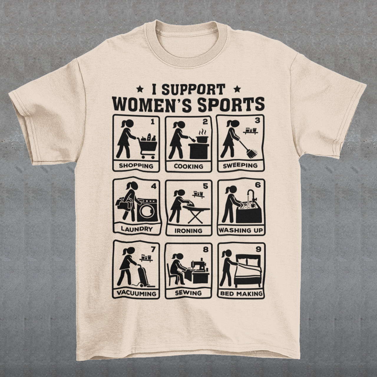 Beige t-shirt featuring the humorous phrase “I SUPPORT WOMEN’S SPORTS” with nine illustrated panels parodying different household activities: shopping, cooking, sweeping, laundry, ironing, washing up, vacuuming, sewing, and bed making. Black graphics create a retro sports-style design with a sarcastic, tongue-in-cheek theme.