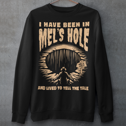 Step into the strange with this quirky and mysterious shirt! Featuring a bold illustration of a curious man peering into a dark, bottomless abyss, this shirt pays homage to the legendary paranormal tale of&nbsp;Mel's Hole — a supposed infinite pit in the wilds of Washington State. The vintage-style artwork is topped with the eerie invitation: "VISIT MEL'S HOLE" in retro tourism font, blending humor, folklore, and a dash of the unexplained.