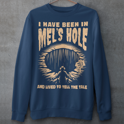 Step into the strange with this quirky and mysterious shirt! Featuring a bold illustration of a curious man peering into a dark, bottomless abyss, this shirt pays homage to the legendary paranormal tale of&nbsp;Mel's Hole — a supposed infinite pit in the wilds of Washington State. The vintage-style artwork is topped with the eerie invitation: "VISIT MEL'S HOLE" in retro tourism font, blending humor, folklore, and a dash of the unexplained.
