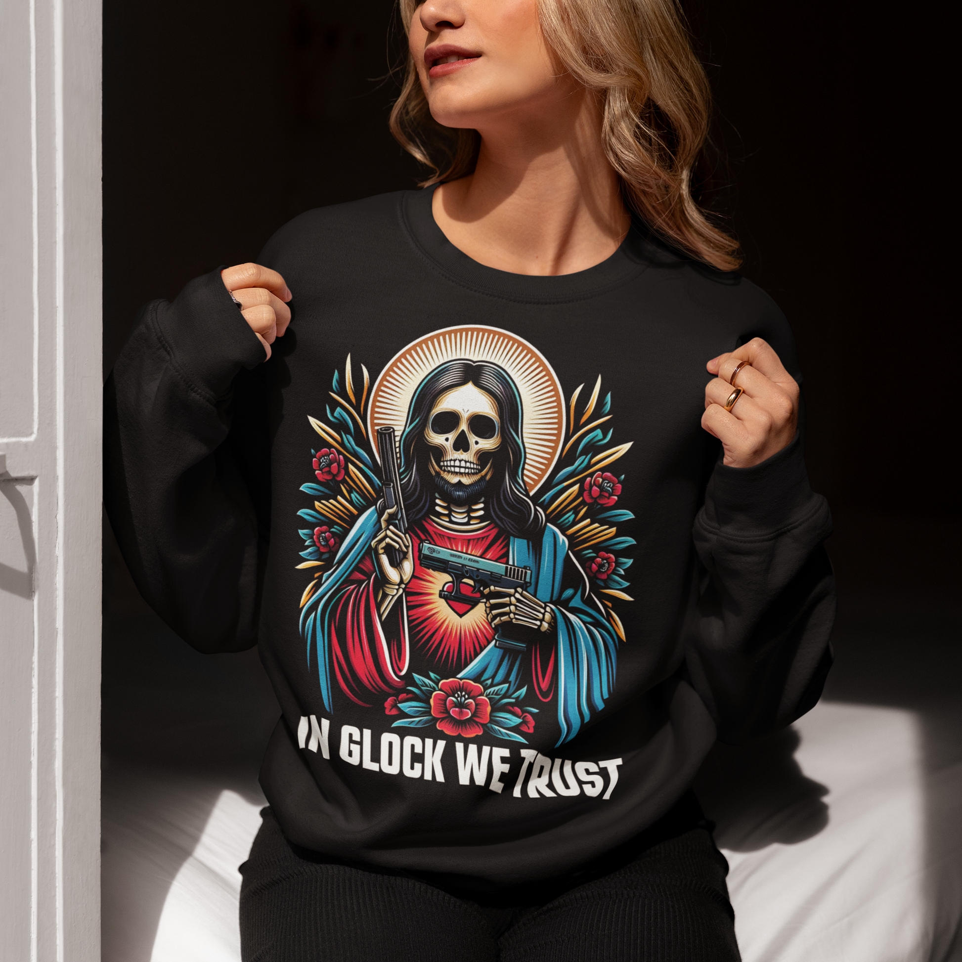 Black sweatshirt of a skeleton Jesus with two guns and text below IN GLOCK WE TRUST. 