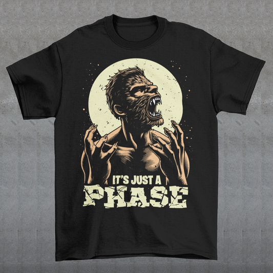 This t-shirt features a dynamic illustration of a man mid-transformation into a fearsome werewolf under the glow of a full moon. His human features contort as claws emerge, fur spreads across his body, and his eyes glow with a supernatural intensity. Below the image, the humorous and clever text reads: "IT'S JUST A PHASE," playfully alluding to both the lunar cycle and the werewolf's transformation.