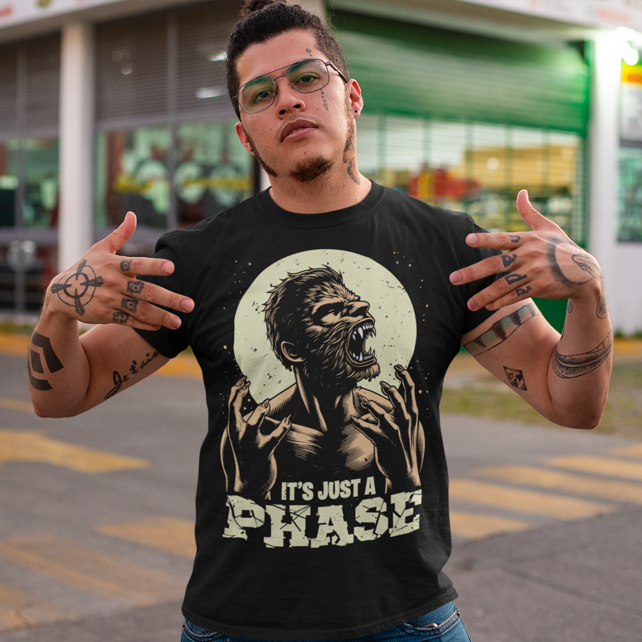 Black t-shirt of a man transforming in to a werewolf with text underneath "IT'S JUST A PHASE."