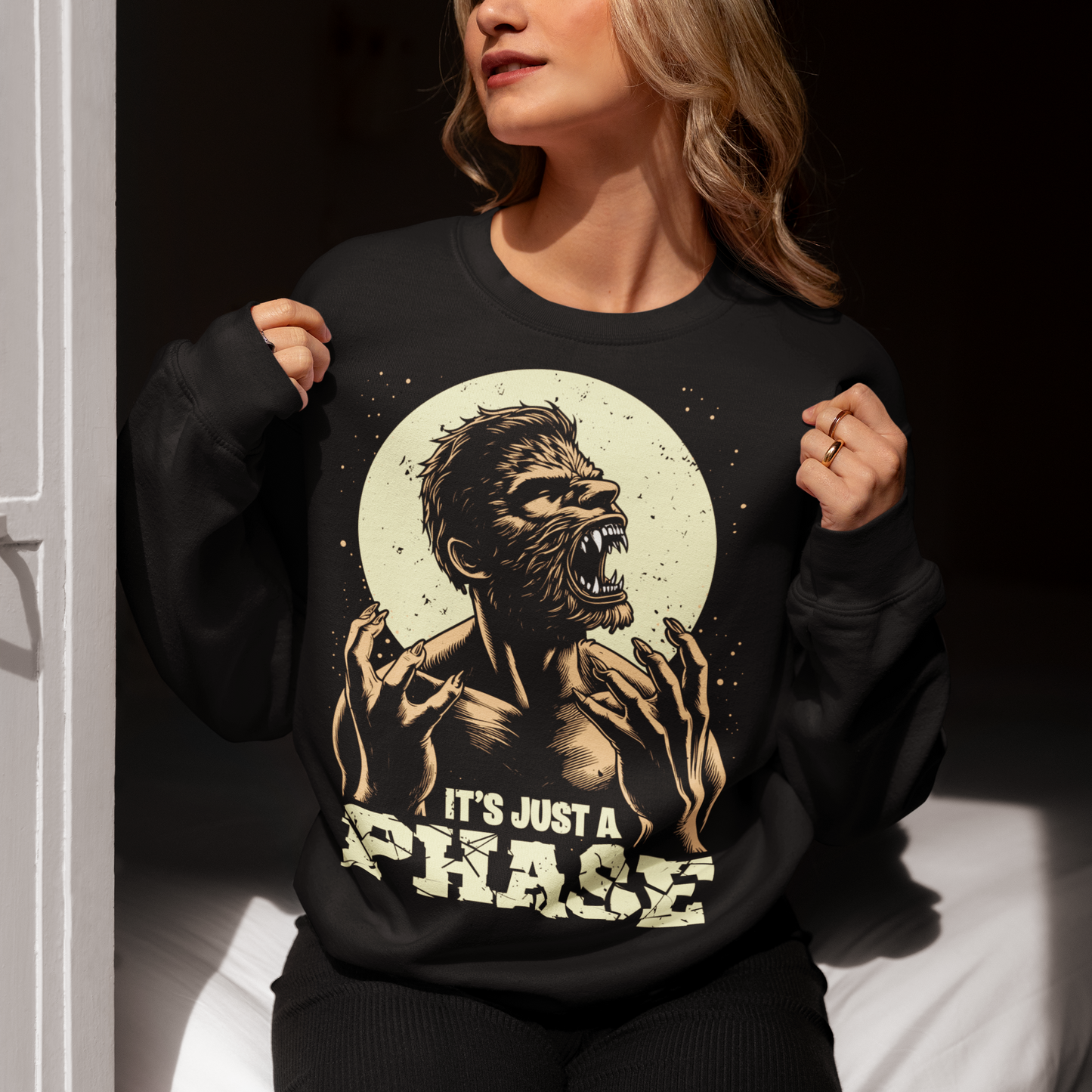 Black sweatshirt of a man transforming in to a werewolf with text underneath "IT'S JUST A PHASE."