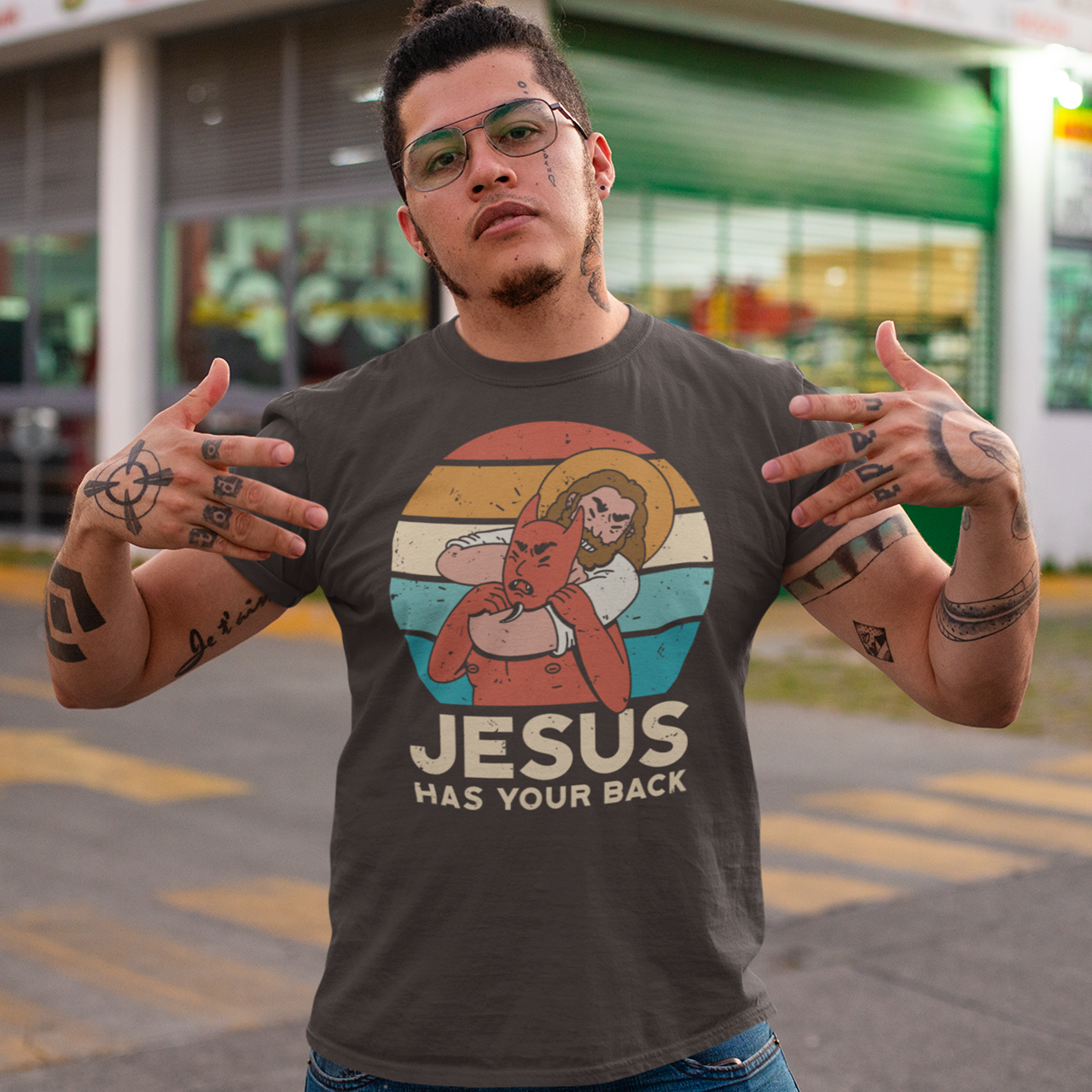 Brown t-shirt of Jesus with Satan in a chokehold in front of a sunset with text "JESUS HAS YOUR BACK".