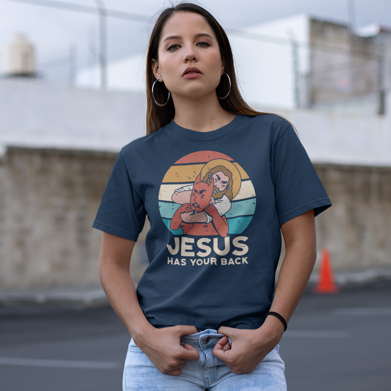 Navy t-shirt of Jesus with Satan in a chokehold in front of a sunset with text "JESUS HAS YOUR BACK".