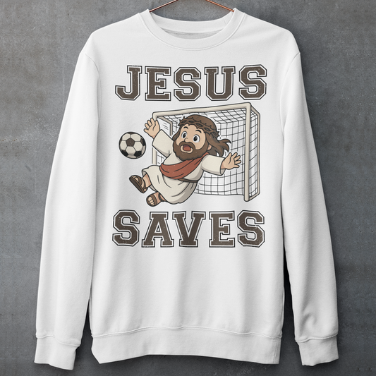 White sweatshirt featuring a cartoon of Jesus as a soccer goalie diving to block a ball in front of a goal net, with the bold text “Jesus Saves” above and below. Fun, humorous Christian design combining faith and sports, printed on a clean white background.