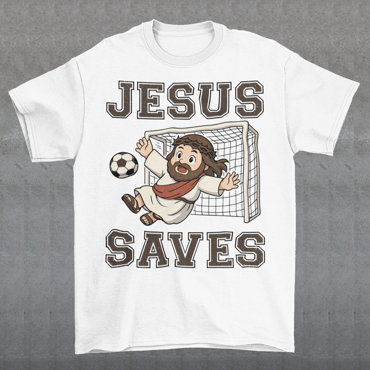 White t-shirt featuring a cartoon of Jesus as a soccer goalie diving to block a ball in front of a goal net, with the bold text “Jesus Saves” above and below. Fun, humorous Christian design combining faith and sports, printed on a clean white background.