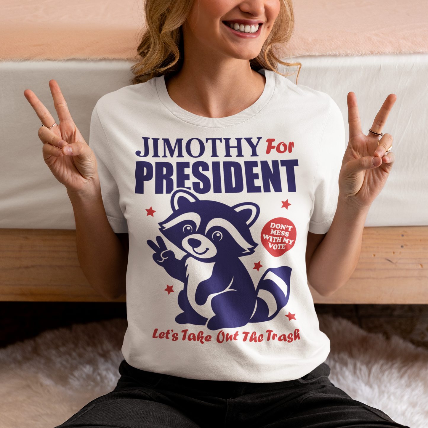White t-shirt featuring a funny Jimothy the raccoon meme design with the text “JIMOTHY FOR PRESIDENT” in bold blue and red lettering. A cartoon raccoon gives a peace sign alongside the slogan “DON’T MESS WITH MY VOTE” and “LET’S TAKE OUT THE TRASH,” with red stars surrounding the patriotic graphic. Perfect for raccoon lovers, meme fans, and political humor enthusiasts.