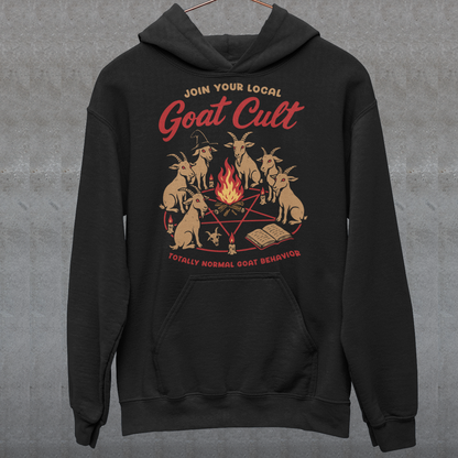 Black hoodie featuring a humorous occult-style graphic of goats gathered in a ritual circle around a fire with candles and symbols. Text reads “Join Your Local Goat Cult” with “Totally Normal Goat Behavior” underneath. The design has a playful spooky aesthetic with cartoon goats, making it a funny and quirky dark humor piece.