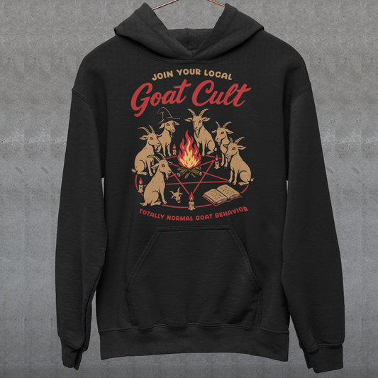 Black hoodie featuring a humorous occult-style graphic of goats gathered in a ritual circle around a fire with candles and symbols. Text reads “Join Your Local Goat Cult” with “Totally Normal Goat Behavior” underneath. The design has a playful spooky aesthetic with cartoon goats, making it a funny and quirky dark humor piece.