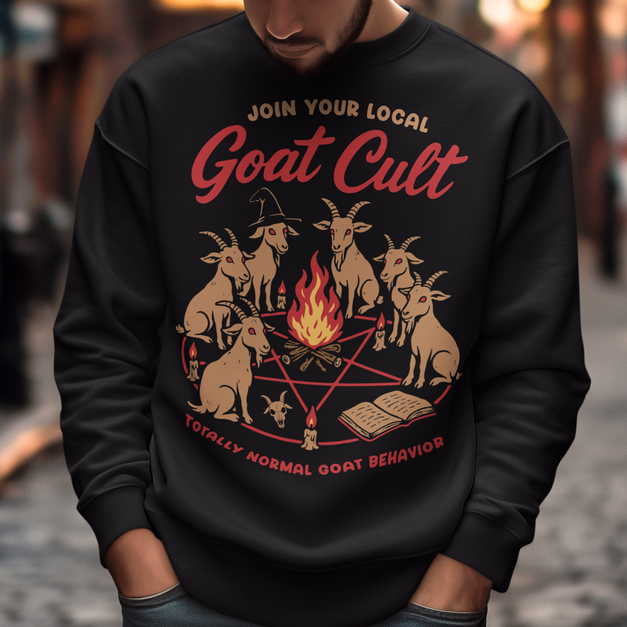 Black sweatshirt featuring a humorous occult-style graphic of goats gathered in a ritual circle around a fire with candles and symbols. Text reads “Join Your Local Goat Cult” with “Totally Normal Goat Behavior” underneath. The design has a playful spooky aesthetic with cartoon goats, making it a funny and quirky dark humor piece.