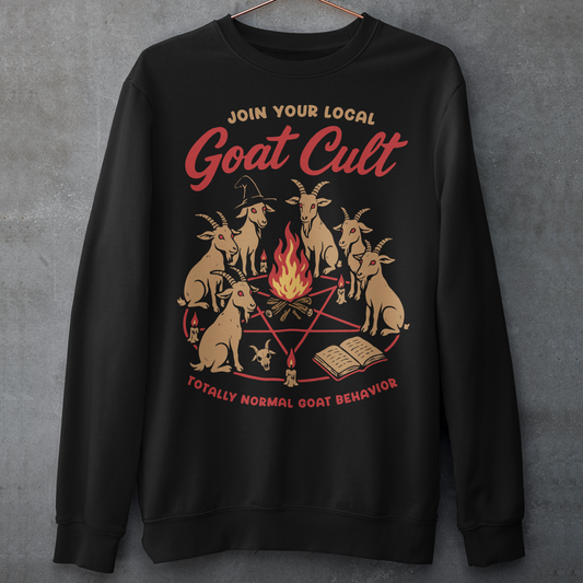 Black sweatshirt featuring a humorous occult-style graphic of goats gathered in a ritual circle around a fire with candles and symbols. Text reads “Join Your Local Goat Cult” with “Totally Normal Goat Behavior” underneath. The design has a playful spooky aesthetic with cartoon goats, making it a funny and quirky dark humor piece.