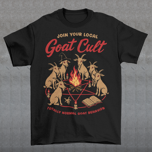 Black t-shirt featuring a humorous occult-style graphic of goats gathered in a ritual circle around a fire with candles and symbols. Text reads “Join Your Local Goat Cult” with “Totally Normal Goat Behavior” underneath. The design has a playful spooky aesthetic with cartoon goats, making it a funny and quirky dark humor piece.
