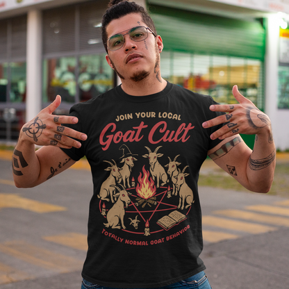 Black t-shirt featuring a humorous occult-style graphic of goats gathered in a ritual circle around a fire with candles and symbols. Text reads “Join Your Local Goat Cult” with “Totally Normal Goat Behavior” underneath. The design has a playful spooky aesthetic with cartoon goats, making it a funny and quirky dark humor piece.