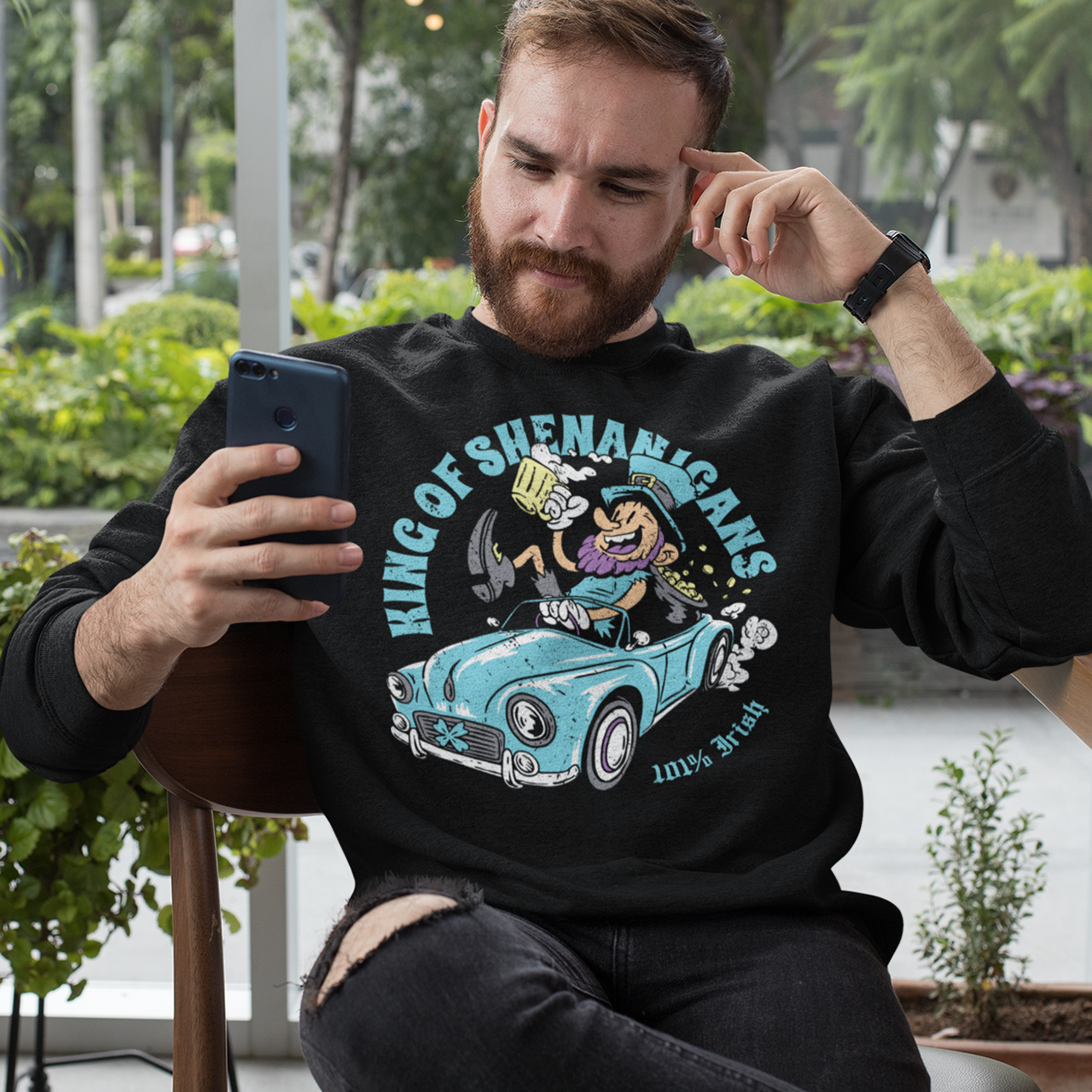 Black sweatshirt with a leprechaun driving a car with text KING OF SHENANIGANS.