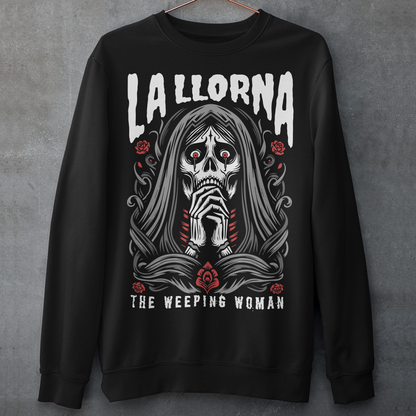 This striking La Llorona sweatshirt features a haunting depiction of the legendary Weeping Woman, her ghostly figure shrouded in mist, with flowing hair and a sorrowful expression as she searches for her lost children. The design captures the eerie, chilling essence of the famous Latin American folktale, blending dark, gothic tones with an ethereal glow. Above the image, bold lettering reads "LA LLORONA", while below, the translation "THE WEEPING WOMAN" adds to the eerie mystique.