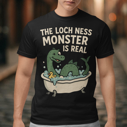 This black graphic tee puts a playful spin on legendary folklore with an adorable take on the Loch Ness Monster. Featuring a cheerful green Nessie splashing in a clawfoot bathtub with bubbles and a rubber duck, the design pairs cozy humor with cryptid charm. Bold lettering declares “The Loch Ness Monster Is Real,” delivering the punchline with confidence and a wink.