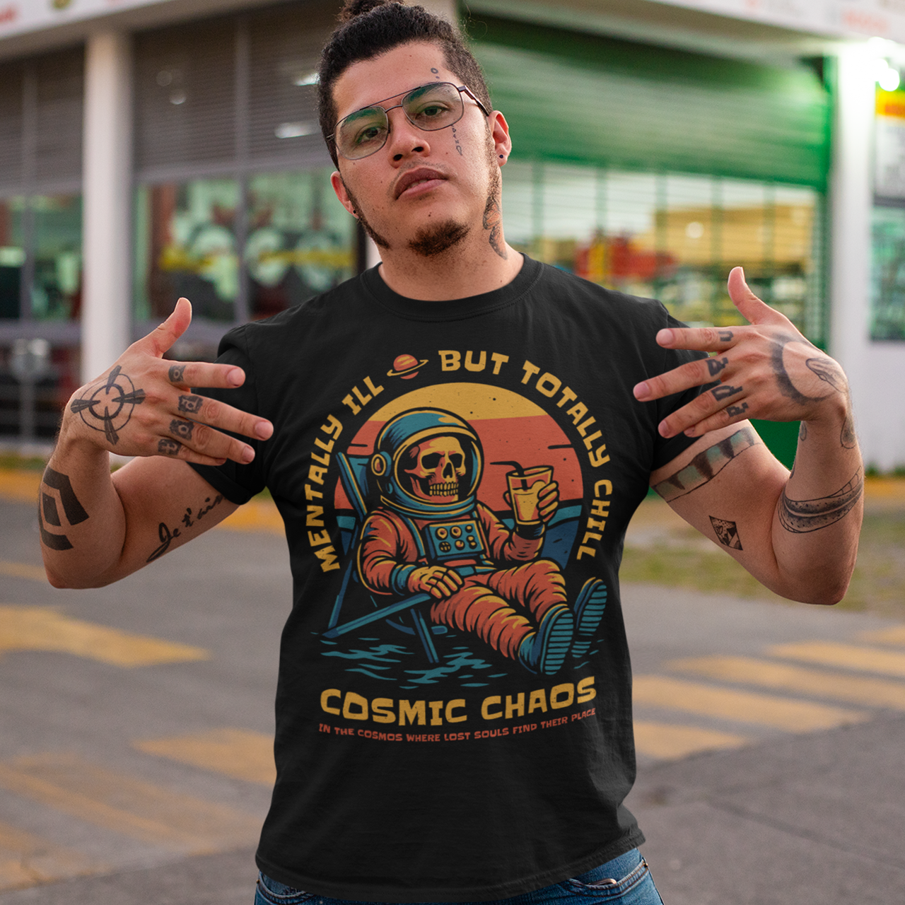 This black graphic tee features a laid-back skeleton astronaut floating in cosmic calm, drink in hand, as the universe quietly burns behind him. Bold retro colors and sunset tones frame the scene, while the phrase “Mentally Ill But Totally Chill” wraps the design with dark humor and self-aware wit. Anchored by the tagline Cosmic Chaos, it feels like a space-age postcard from the edge of existence.