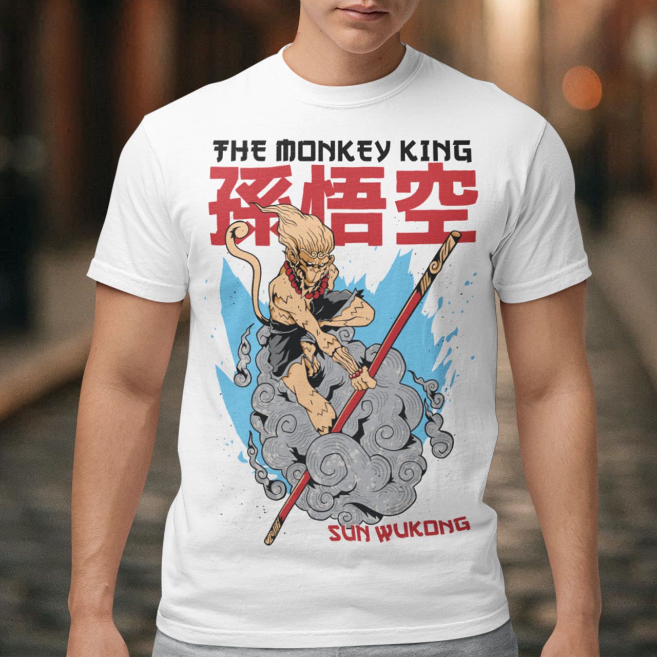 White t-shirt featuring a bold anime-inspired Sun Wukong design with the text “The Monkey King” and “Sun Wukong.” The artwork shows the legendary Monkey King riding swirling clouds while wielding his magical staff, set against large red Chinese characters and blue accents. A dynamic mythological graphic perfect for fans of Journey to the West, anime art, Chinese folklore, martial arts, and fantasy streetwear.