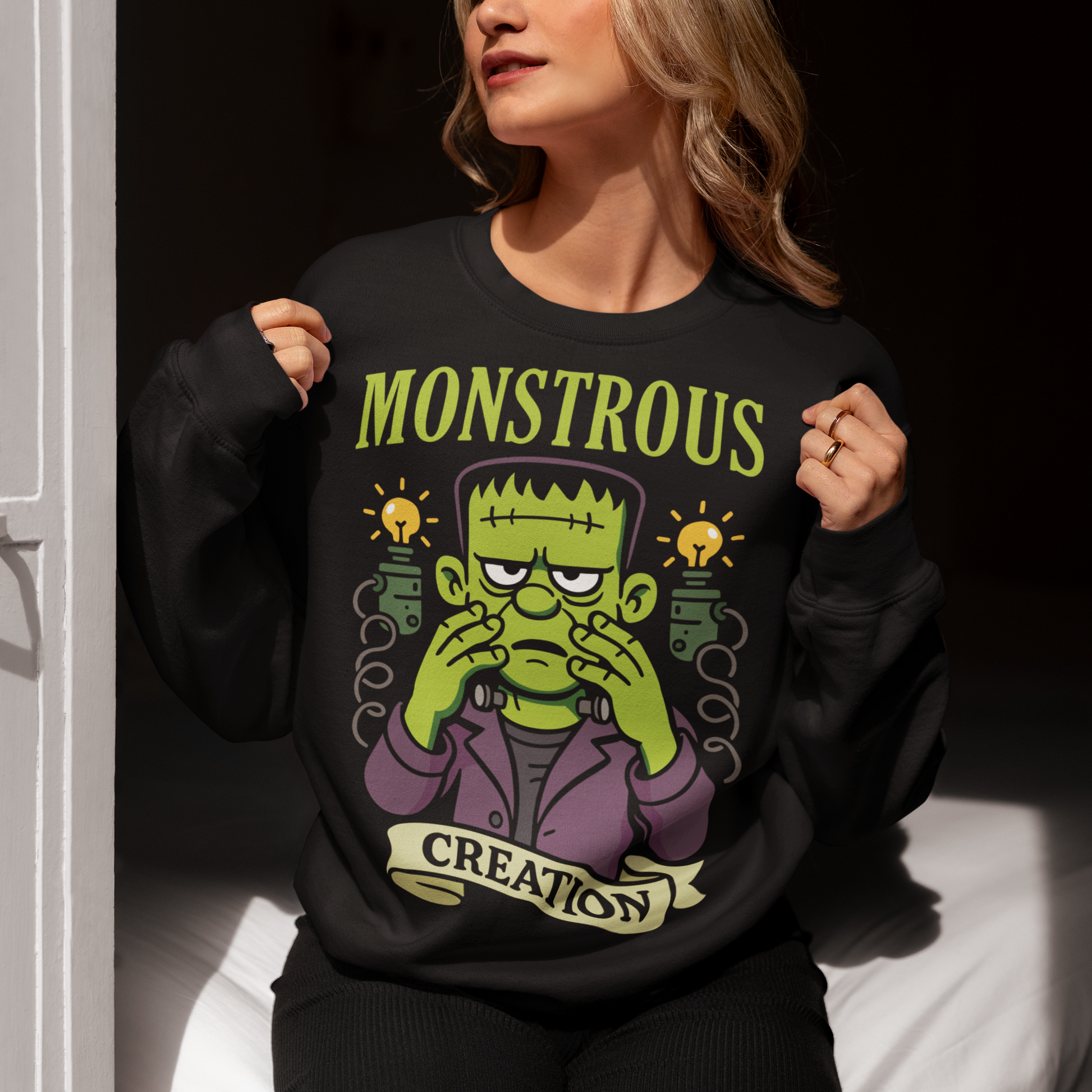 Monstrous creation sweatshirt - Frankenstein shirt. Bring a spark of classic horror to your wardrobe with this bold “Monstrous Creation” sweatshirt. Featuring a grumpy, stitched-up Frankenstein brought to life in a playful cartoon style, this design is a fun tribute to vintage horror with a modern, humorous twist. Surrounded by crackling energy and glowing lab elements, the character captures that iconic “it’s alive!” moment, but with a perfectly unimpressed expression that steals the show.
