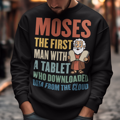 Black sweatshirt featuring a humorous graphic of Moses holding stone tablets with colorful text that reads “Moses the first man with a tablet who downloaded data from the cloud.” The design uses a playful, retro style with multicolored lettering and a cartoon illustration, combining biblical imagery with modern tech humor.