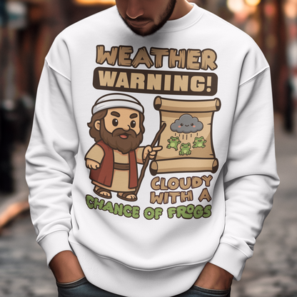 White sweatshirt featuring a cute cartoon Moses pointing at a weather scroll that shows a smiling rain cloud and falling frogs. The text reads “Weather Warning! Cloudy With a Chance of Frogs.” The design uses playful retro colors with funny biblical humor inspired by the plague of frogs story.