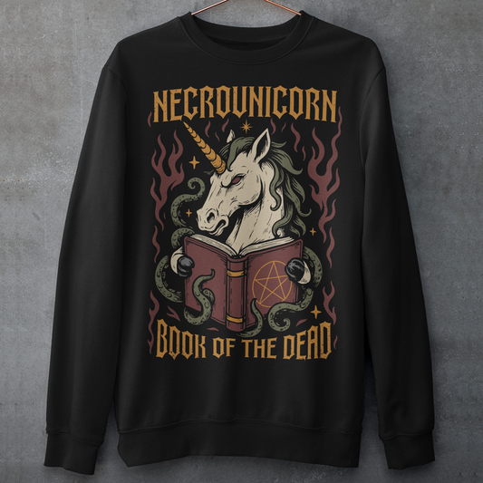 Black sweatshirt featuring a dark fantasy graphic of an evil unicorn reading a spellbook with a pentagram symbol. The design includes flames, tentacles, stars, and gothic lettering reading “Necrounicorn” and “Book of the Dead.” Spooky occult-inspired artwork with horror, witchcore, and fantasy aesthetics.