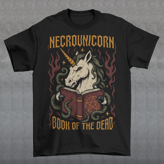 Black t-shirt featuring a dark fantasy graphic of an evil unicorn reading a spellbook with a pentagram symbol. The design includes flames, tentacles, stars, and gothic lettering reading “Necrounicorn” and “Book of the Dead.” Spooky occult-inspired artwork with horror, witchcore, and fantasy aesthetics.
