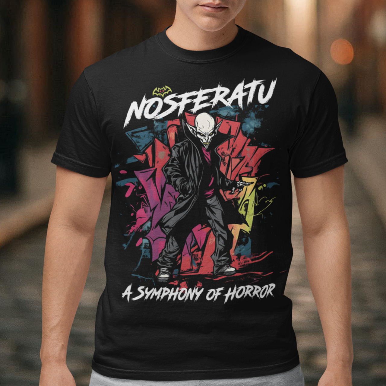 This bold graffiti-style Nosferatu T-Shirt fuses street art with classic horror. The design features a menacing, stylized depiction of Count Orlok with exaggerated, sharp features rendered in vibrant sprays and drips of color, mimicking the gritty texture of urban graffiti. Above the design, the text "NOSFERATU" stands out in bold, dripping block letters, while below, the phrase "A SYMPHONY OF HORROR" is written in an ominous, hand-scrawled font.