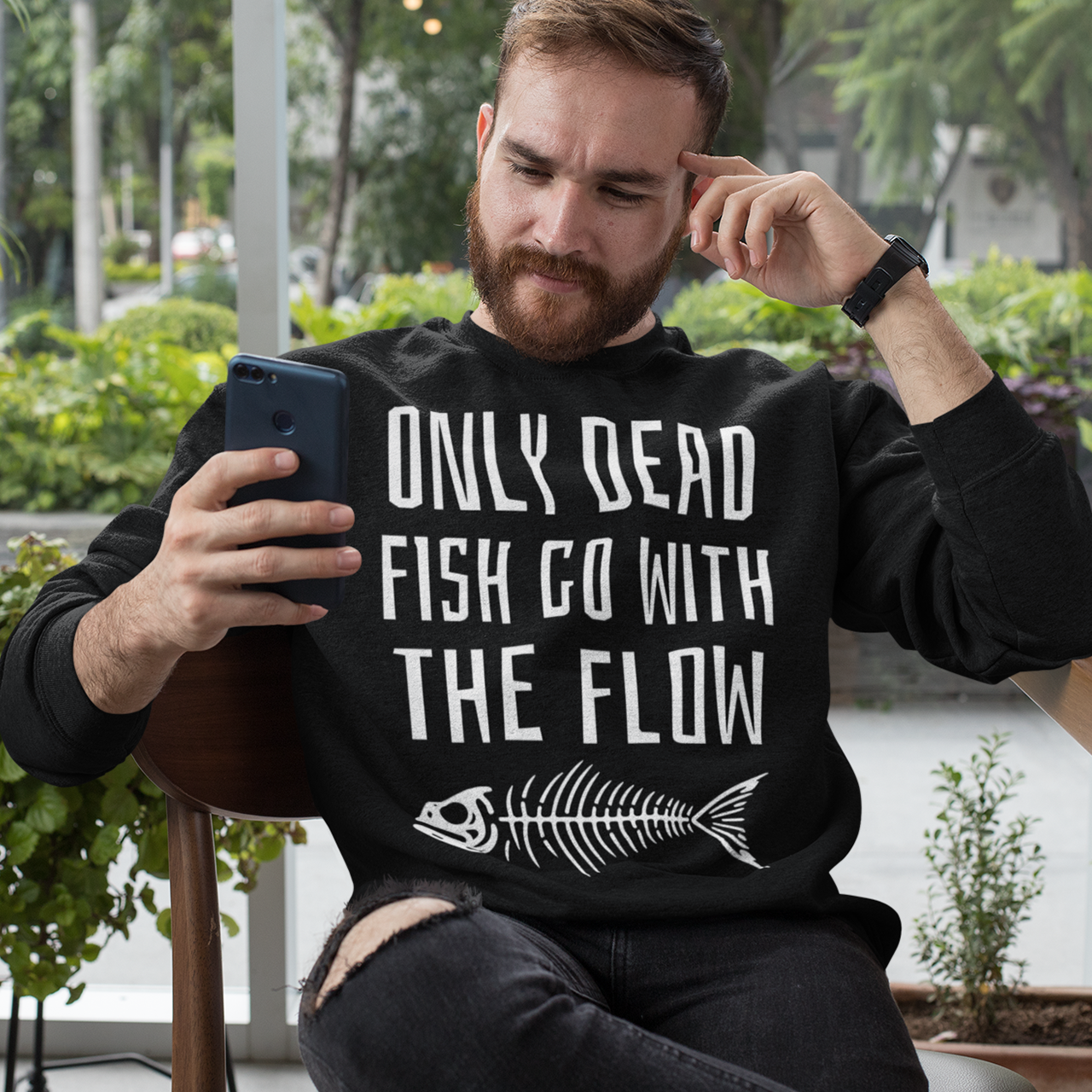 Black sweatshirt of a fish skeleton with text above ONLY DEAD FISH GO WITH THE FLOW.