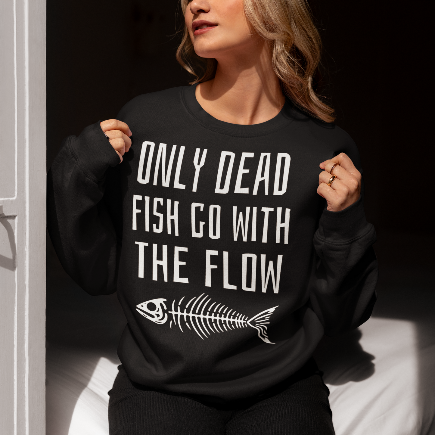 Black sweatshirt of a fish skeleton with text above ONLY DEAD FISH GO WITH THE FLOW.