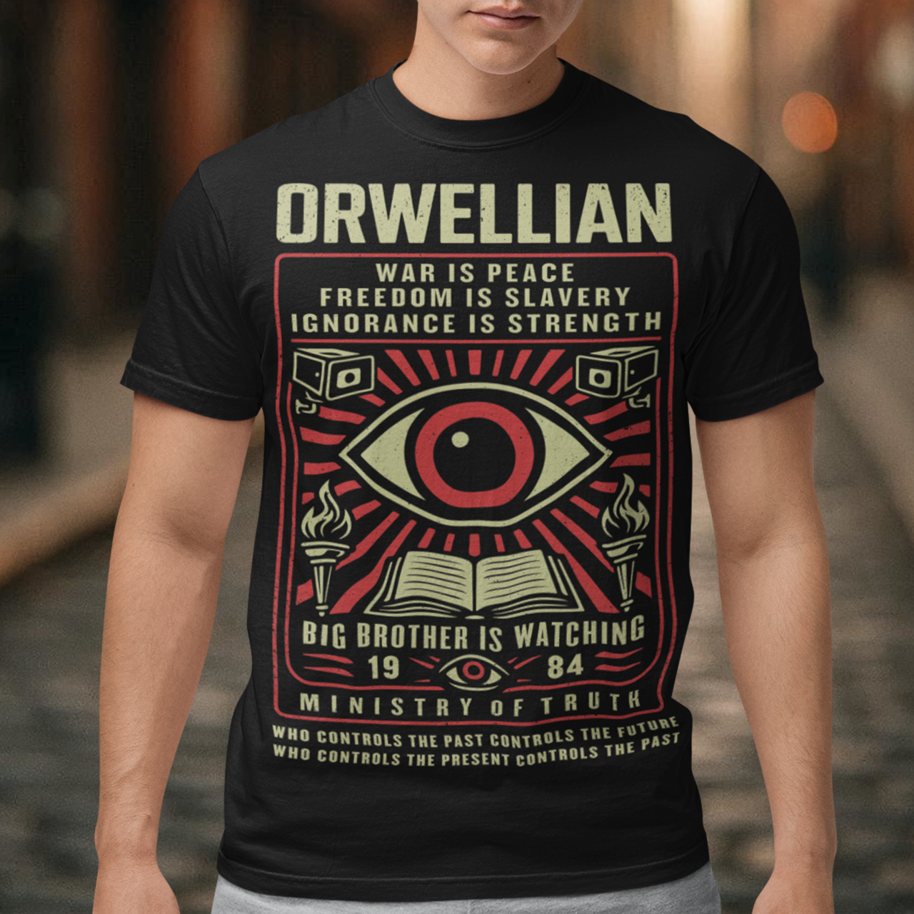 This black shirt channels the unsettling spirit of George Orwell’s 1984 with bold, high-contrast artwork and iconic slogans that refuse to whisper. The all-seeing eye dominates the design, flanked by surveillance cameras, burning torches, and an open book, a visual chorus of control, truth, and resistance. Phrases like “War Is Peace,” “Freedom Is Slavery,” and “Ignorance Is Strength” sit beneath the unmistakable warning: Big Brother Is Watching.