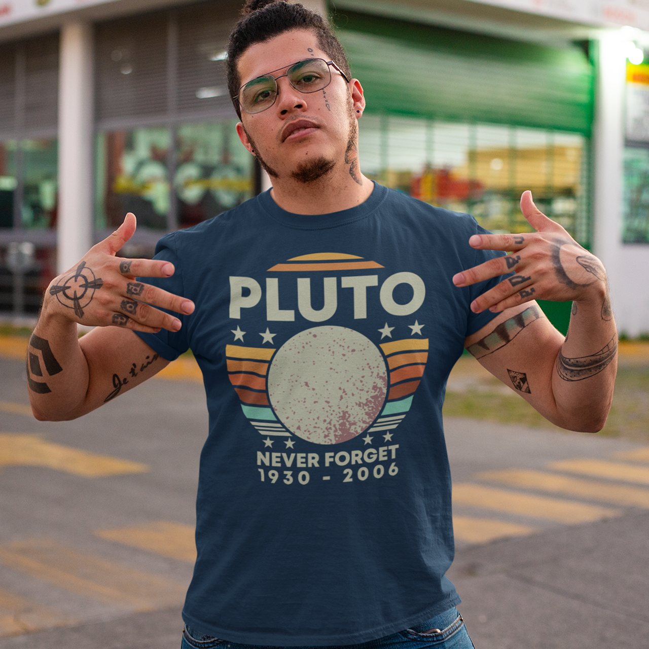 Navy t-shirt of Pluto in front of a retro sun with text above PLUTO and text underneath NEVER FORGET 1930 - 2006.