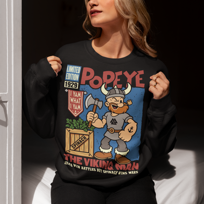 Channel old-school cartoon strength with this bold Popeye Viking graphic sweatshirt, where classic sailor swagger sails north into Viking territory. This playful design features a bearded Viking version of the legendary spinach-powered sailor, proudly gripping an axe beside a crate of spinach. With retro comic styling, vintage textures, and the iconic phrase “I Yam What I Yam,” the artwork celebrates the timeless humor and toughness that made the character famous.