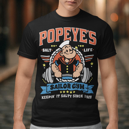 Hit the gym like a legend with the Popeye’s Sailor Gym tee! Inspired by everyone’s favorite spinach-powered sailor, this shirt is perfect for lifting, lounging, or showing off your old-school strength. Featuring a vintage-style graphic of Popeye pumping iron with the slogan "Keepin' It Salty Since 1929", this tee brings serious muscle and serious nostalgia.