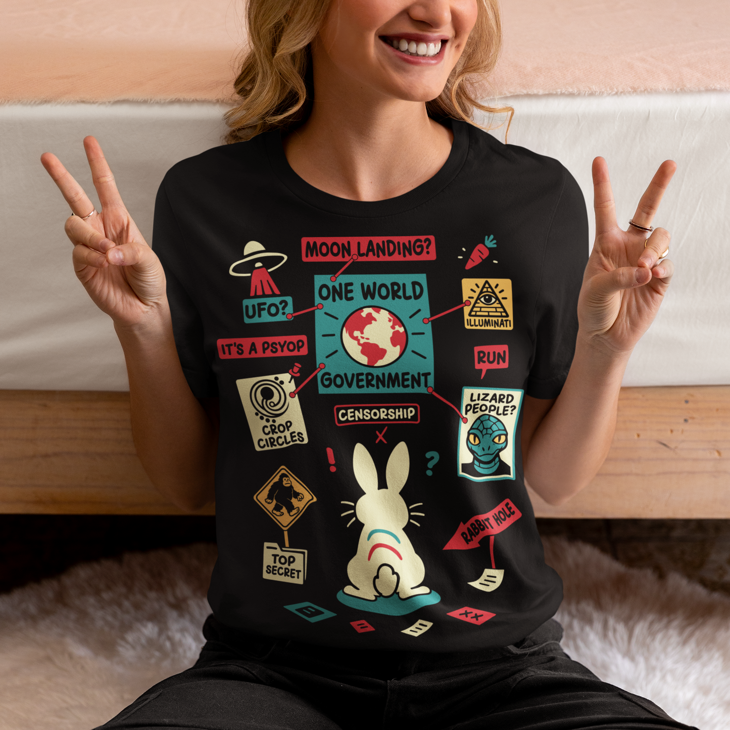 Black t-shirt featuring a humorous conspiracy theory design with a confused rabbit standing before a bulletin board connected by red strings. The artwork includes UFOs, moon landing, lizard people, crop circles, Bigfoot, Illuminati, censorship, psyops, and rabbit hole references in a colorful retro style. A funny graphic tee for fans of conspiracies, cryptids, aliens, internet memes, and mystery-themed humor.
