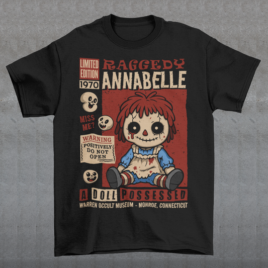 Stay cozy with a creepy-cute twist in this horror-themed t-shirt featuring a distressed vintage doll design inspired by classic haunted-toy aesthetics. The graphic showcases a stitched, wide-eyed rag-style doll surrounded by spooky warning labels and retro horror elements, giving it the look of an old collectible poster. This shirt is ideal for horror fans, lovers of eerie artwork, and anyone who enjoys adding a little dark charm to their wardrobe.