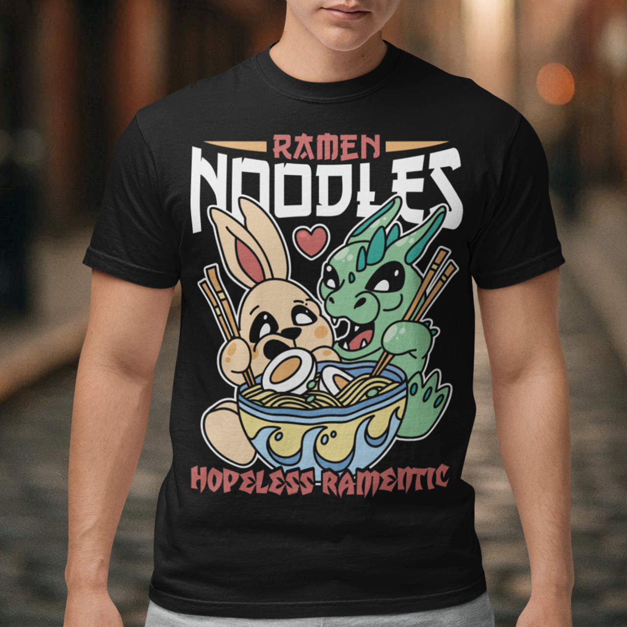 Indulge in the whimsical harmony of culinary delight and fantastical companionship with our "Ramen Noodles" t-shirt featuring a captivating scene of a dragon and a rabbit sharing a bowl of savory ramen. This unique and charming design seamlessly blends the worlds of mythical creatures and culinary passion to create a wearable work of art. Above the delightful duo, the bold text proudly declares "RAMEN NOODLES," setting the stage for the central theme of this captivating tee.