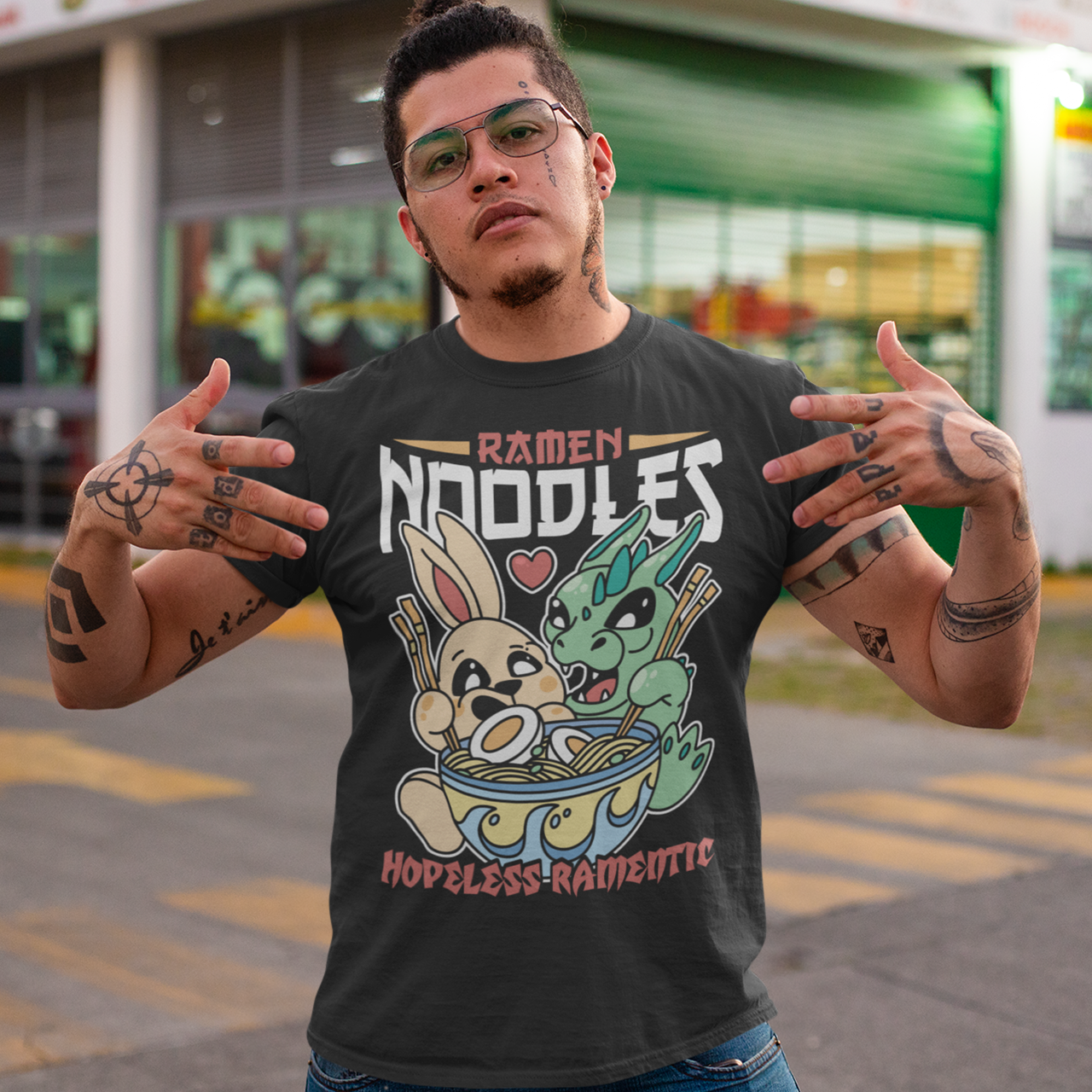 Indulge in the whimsical harmony of culinary delight and fantastical companionship with our "Ramen Noodles" t-shirt featuring a captivating scene of a dragon and a rabbit sharing a bowl of savory ramen. This unique and charming design seamlessly blends the worlds of mythical creatures and culinary passion to create a wearable work of art. Above the delightful duo, the bold text proudly declares "RAMEN NOODLES," setting the stage for the central theme of this captivating tee.