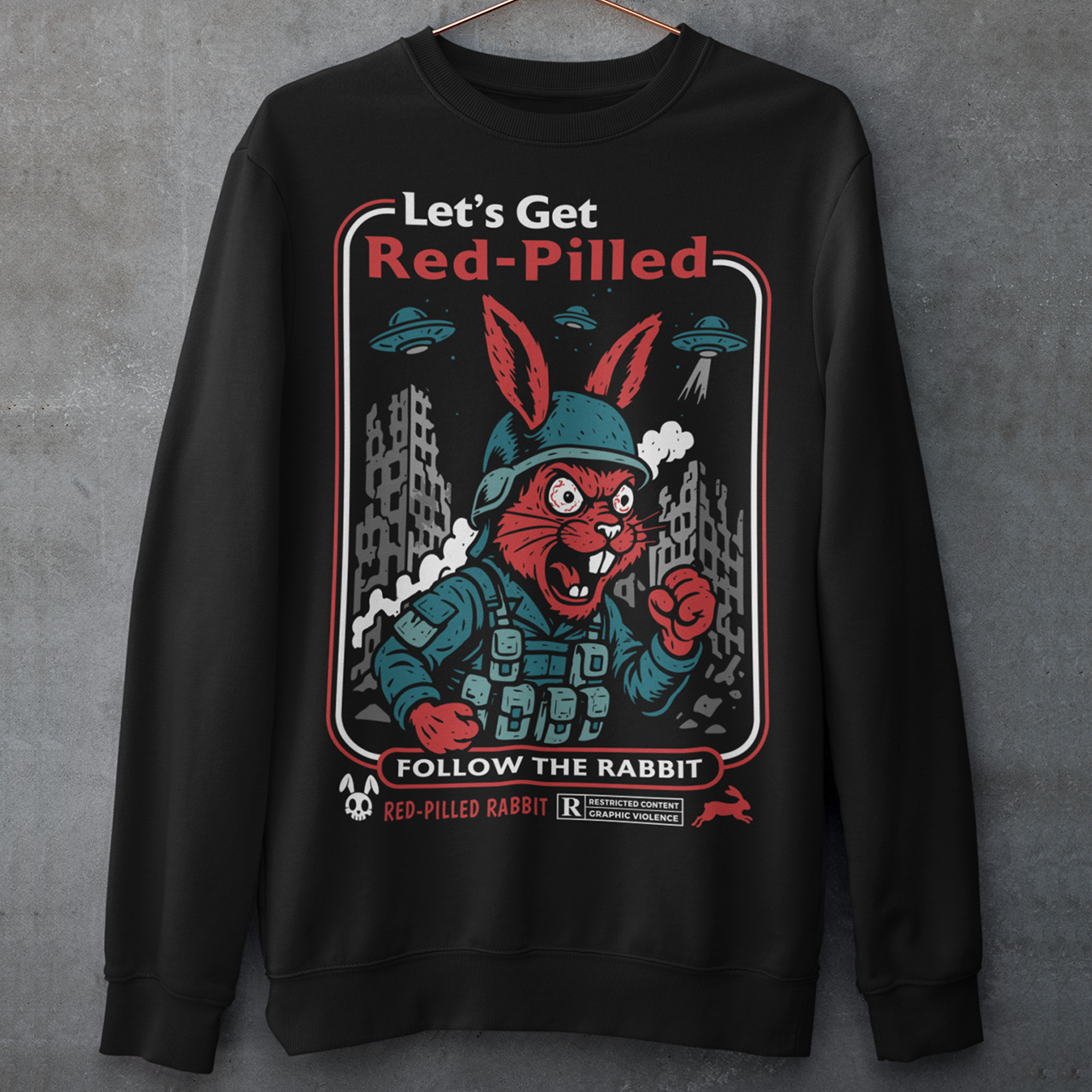This black graphic sweatshirt dives headfirst down the rabbit hole. Featuring a fierce, red-eyed rabbit geared up like a rebel soldier, the design blends sci-fi paranoia, retro poster aesthetics, and counterculture attitude. Bold lettering reads “Let’s Get Red-Pilled” with “Follow the Rabbit” anchoring the scene, while crumbling cityscapes and hovering UFOs set a dystopian, mind-bending mood. This shirt feels like a lost propaganda poster from an alternate reality.