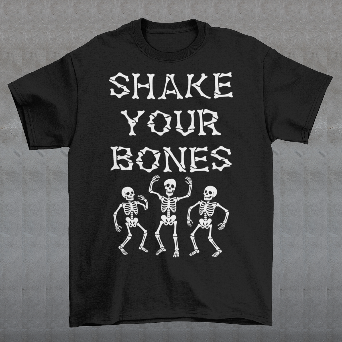 Black t-shirt featuring bold distressed lettering reading “SHAKE YOUR BONES” above three dancing skeletons. The vintage-inspired graphic uses white artwork on a black background, creating a spooky gothic look with dark humor. Perfect for Halloween, skeleton lovers, goth fashion fans, spooky season, parties, concerts, and anyone who likes their wardrobe with a little skeletal attitude.