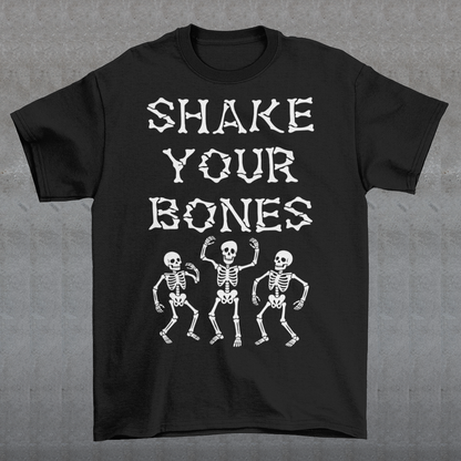 Black t-shirt featuring bold distressed lettering reading “SHAKE YOUR BONES” above three dancing skeletons. The vintage-inspired graphic uses white artwork on a black background, creating a spooky gothic look with dark humor. Perfect for Halloween, skeleton lovers, goth fashion fans, spooky season, parties, concerts, and anyone who likes their wardrobe with a little skeletal attitude.