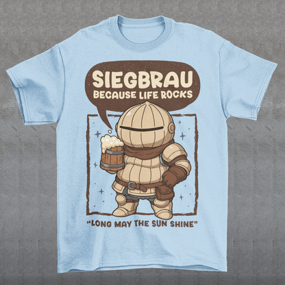 Light blue t-shirt featuring a cute, chibi-style armored knight Siegmeyer of Catarina holding a frothy beer mug. Above the character, bold text reads “Siegbrau because life rocks,” with smaller text below saying “Long may the sun shine.” The design has a playful fantasy theme with soft brown tones and a hand-drawn style, appealing to gamers and fans of medieval or RPG-inspired humor.