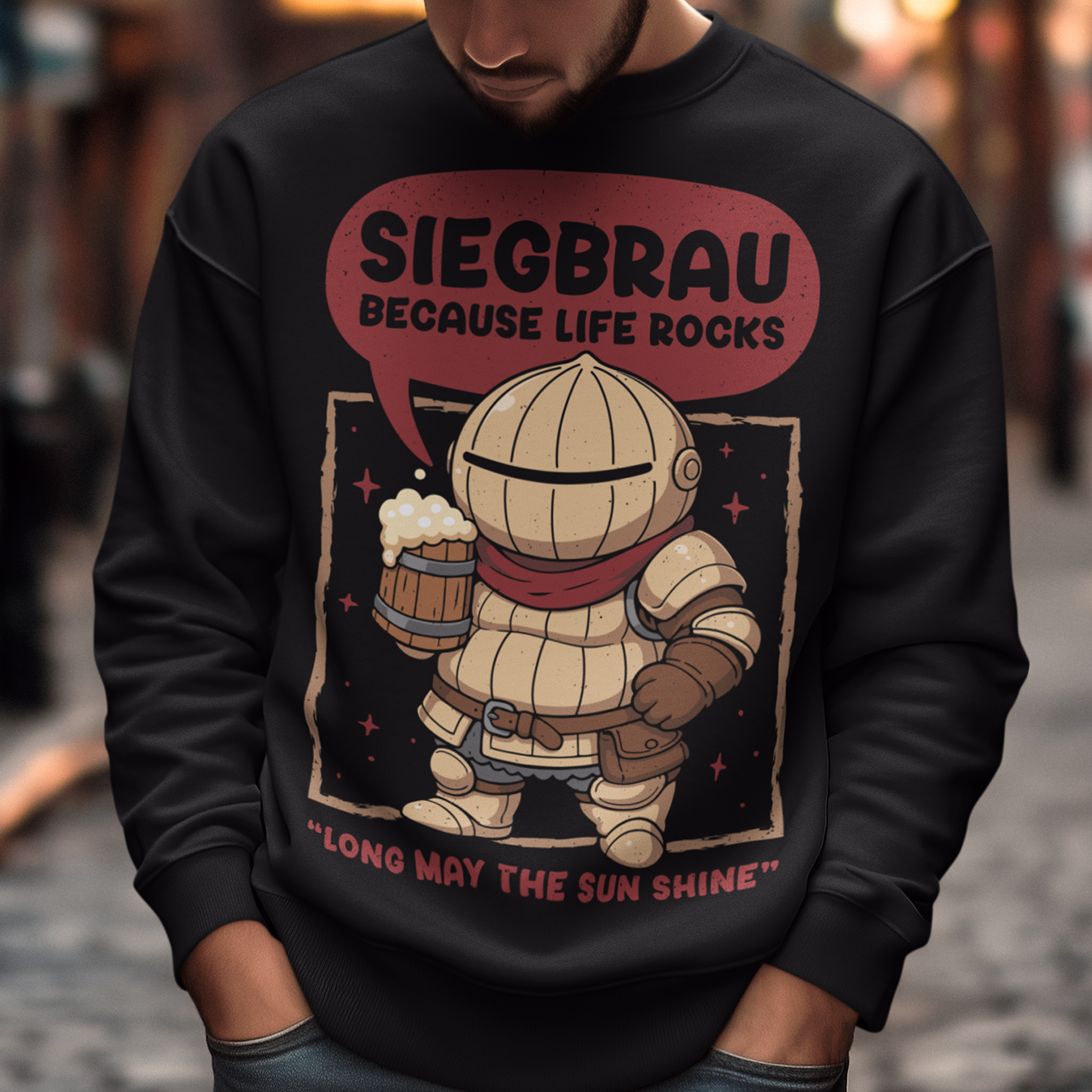 Black sweatshirt featuring a cute, chibi-style armored knight Siegmeyer of Catarina holding a frothy beer mug. Above the character, bold text reads “Siegbrau because life rocks,” with smaller text below saying “Long may the sun shine.” The design has a playful fantasy theme with soft red tones and a hand-drawn style, appealing to gamers and fans of medieval or RPG-inspired humor.