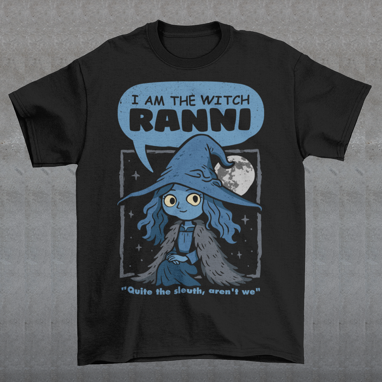 Black t-shirt featuring a cute blue witch character with large eyes wearing a pointed hat and cloak, set against a night sky with a full moon and stars. Text above reads “I AM THE WITCH RANNI,” with a smaller quote below saying “Quite the sleuth, aren’t we.” The design has a dark fantasy, game-inspired style with soft blue tones and a whimsical, mystical aesthetic.